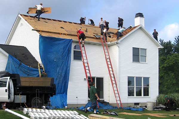 Roofing crew doing a roof replacement on a white, two-story home
