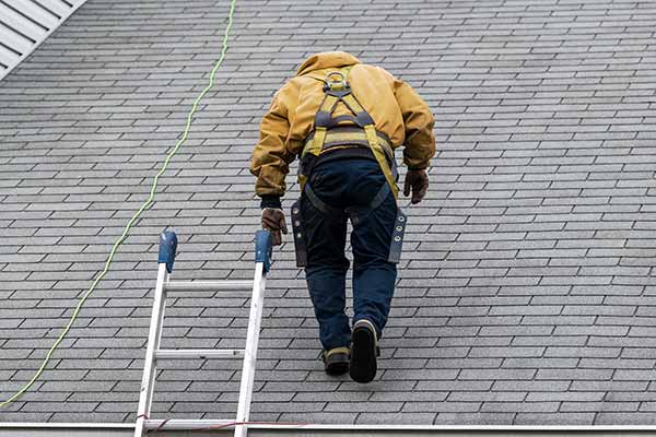 Worker walking on a residential roof while inspecting it