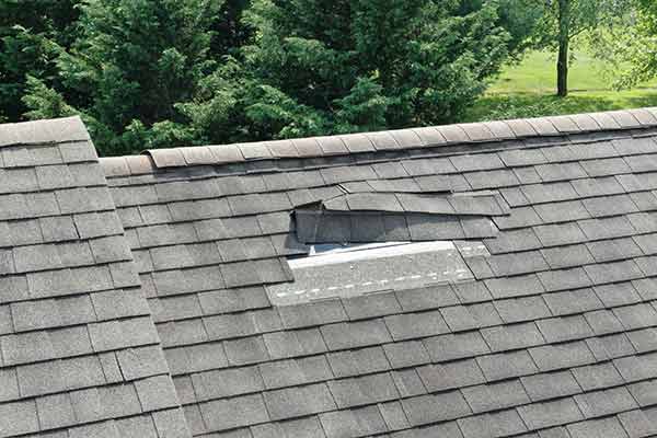 Close up of a residential roof with missing and loose shingles